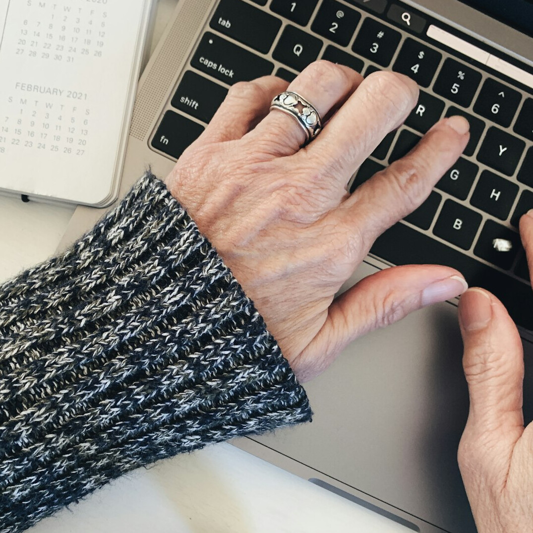 Hands typing on a laptop with notes beside it