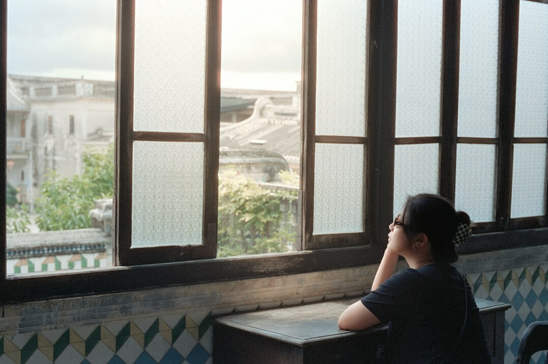 Woman writing notes in a planner near a window